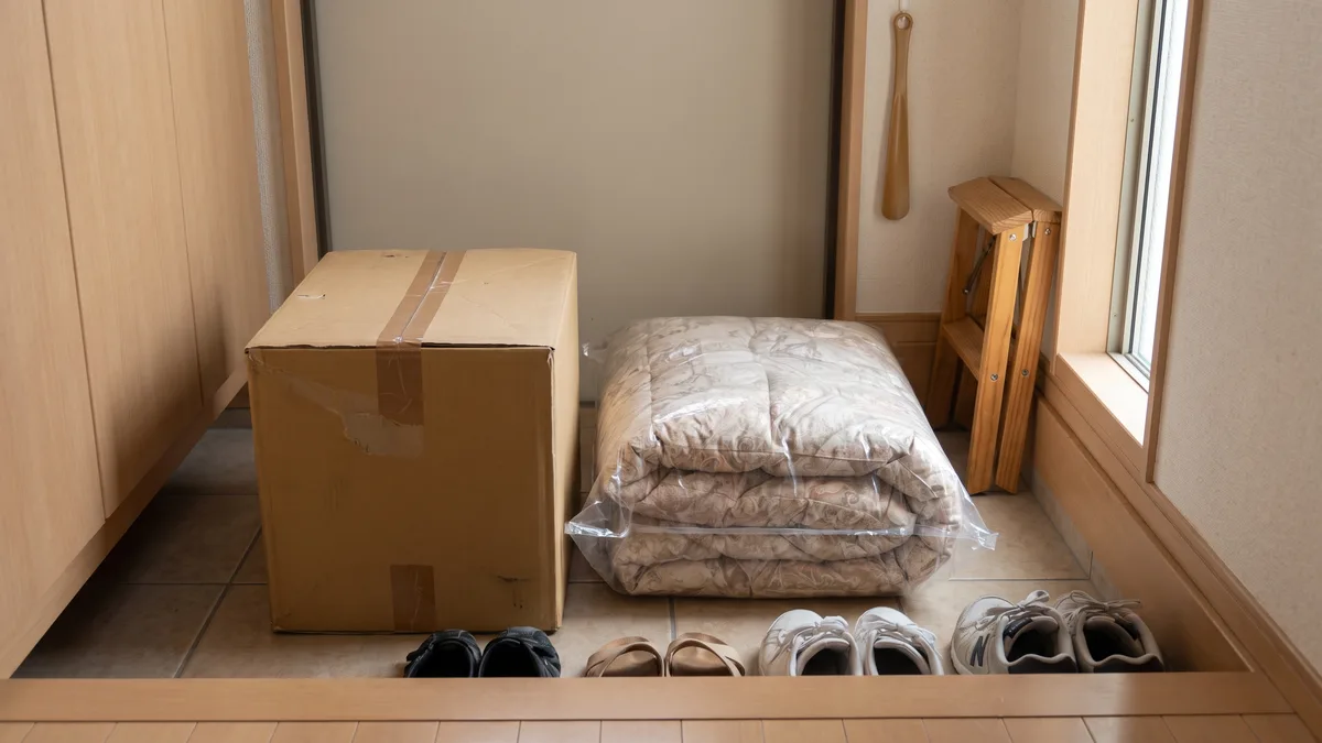 玄関に置いた、集荷を待つ段ボール箱と袋に入れた布団（イメージ）